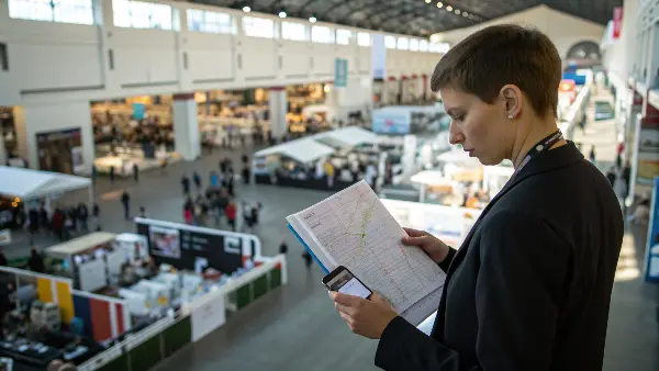 A person at a desk planning with a laptop and a list of trade show exhibitors